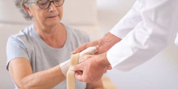 Infirmier bandant un poignet blessé d'une patiente.