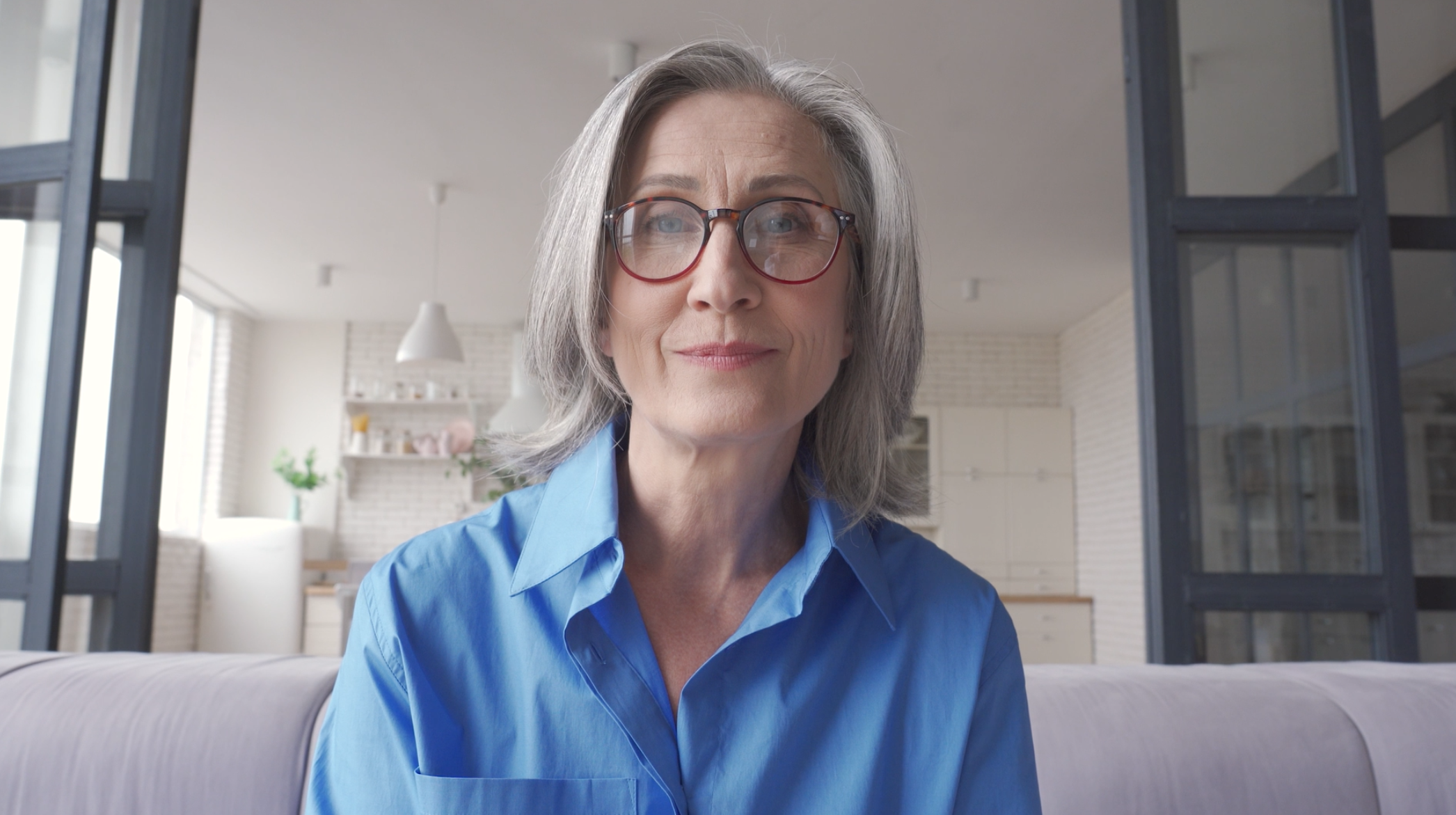 Femme souriante avec des lunettes dans un intérieur.