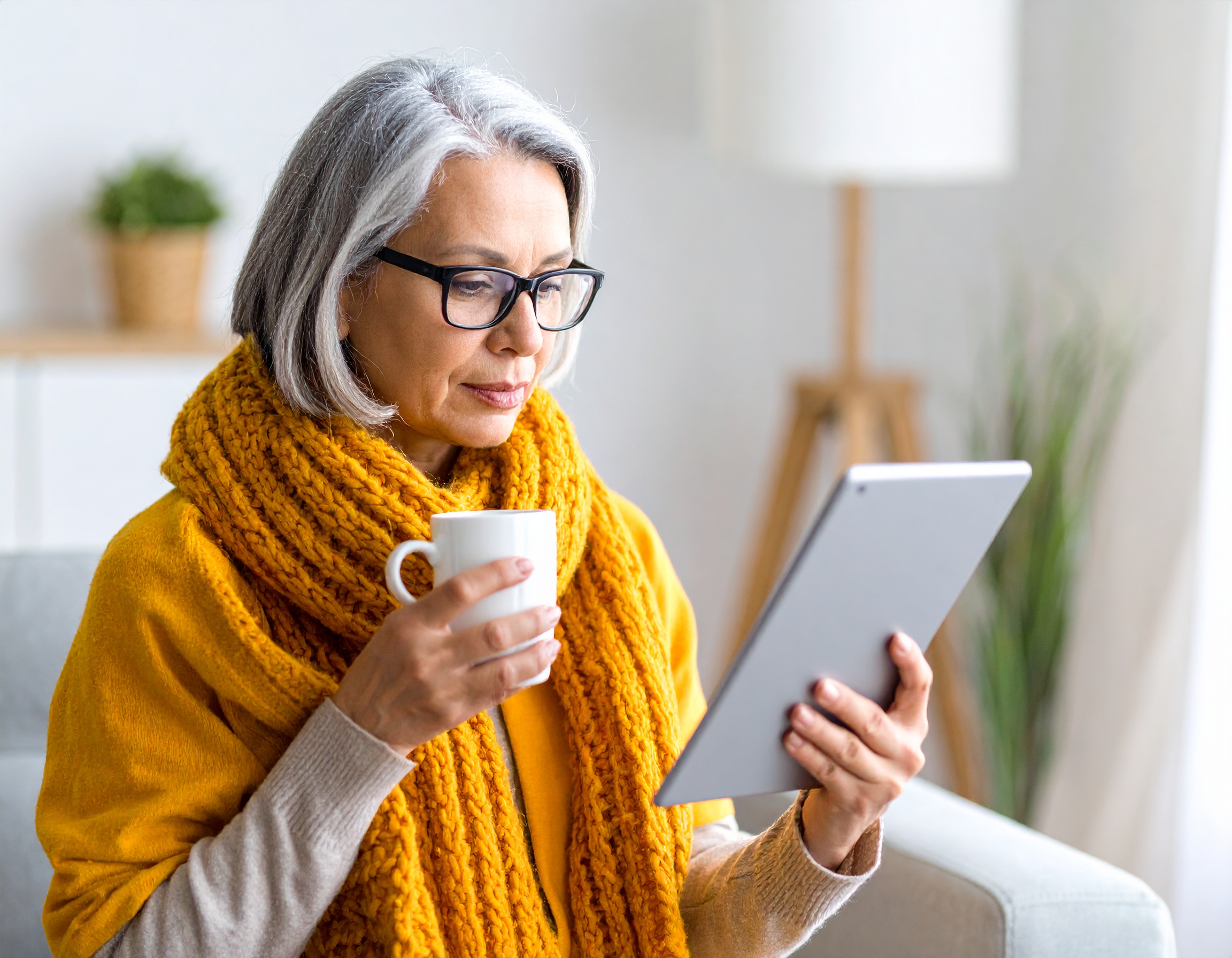 Femme âgée avec tablette et tasse de café