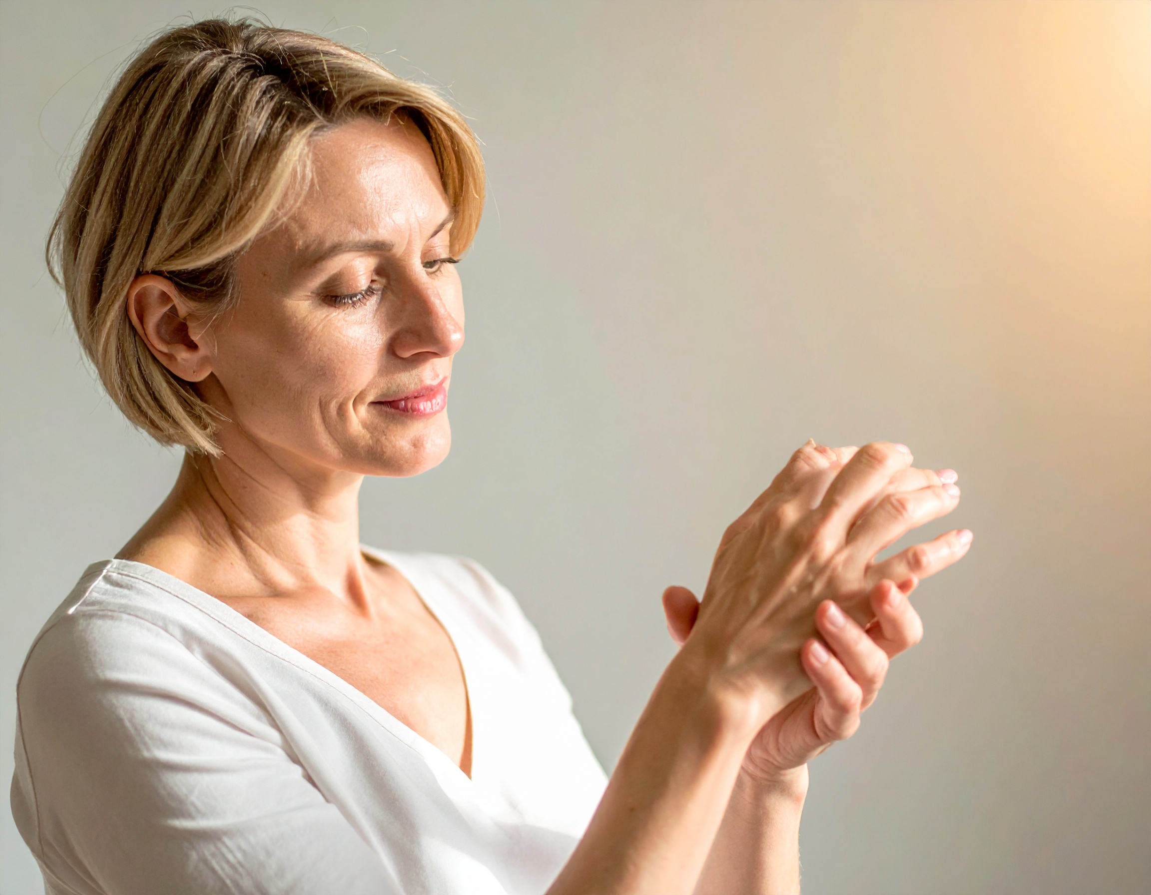 Femme souriante massant ses mains.