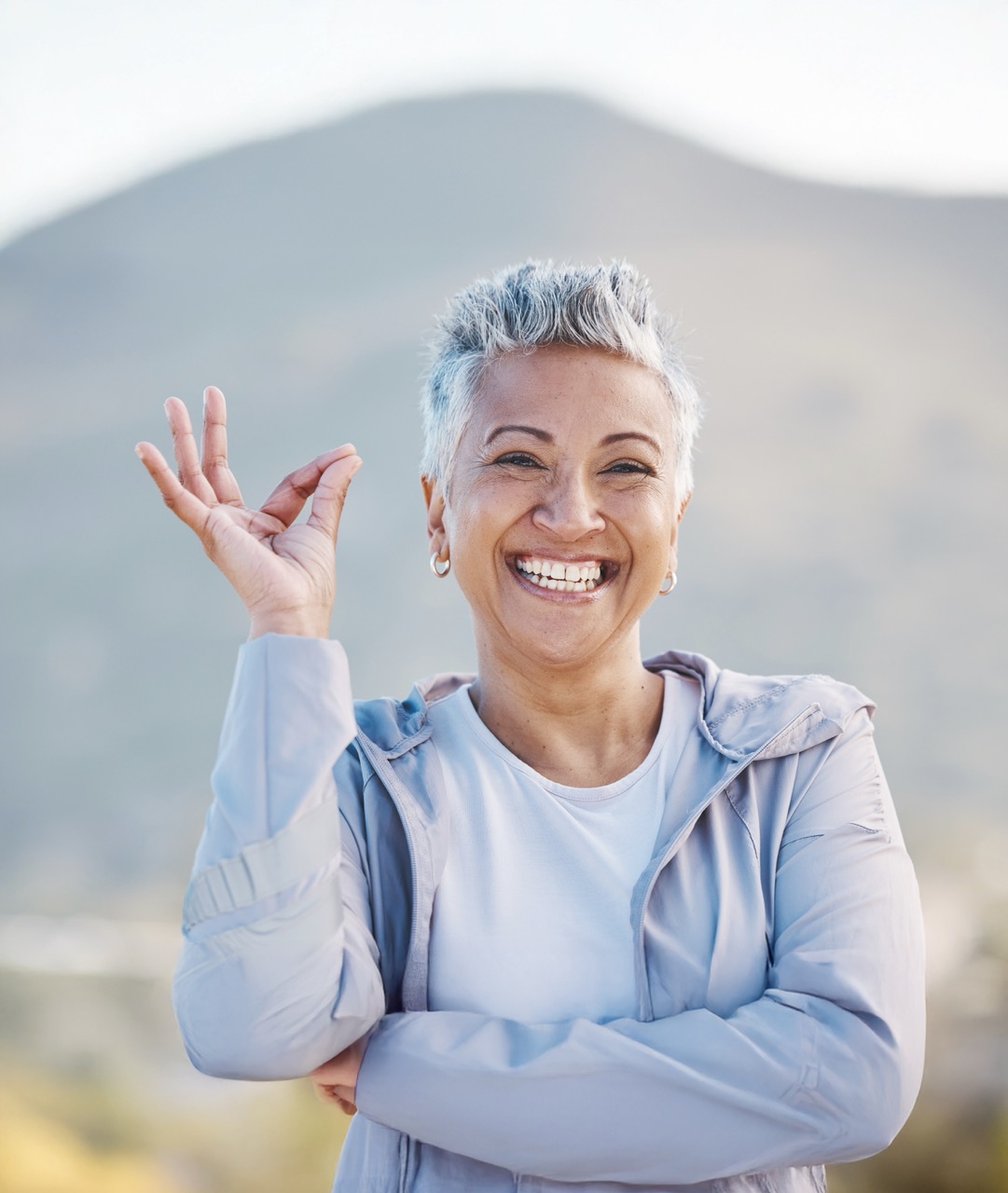 Femme souriante avec un geste positif en plein air.