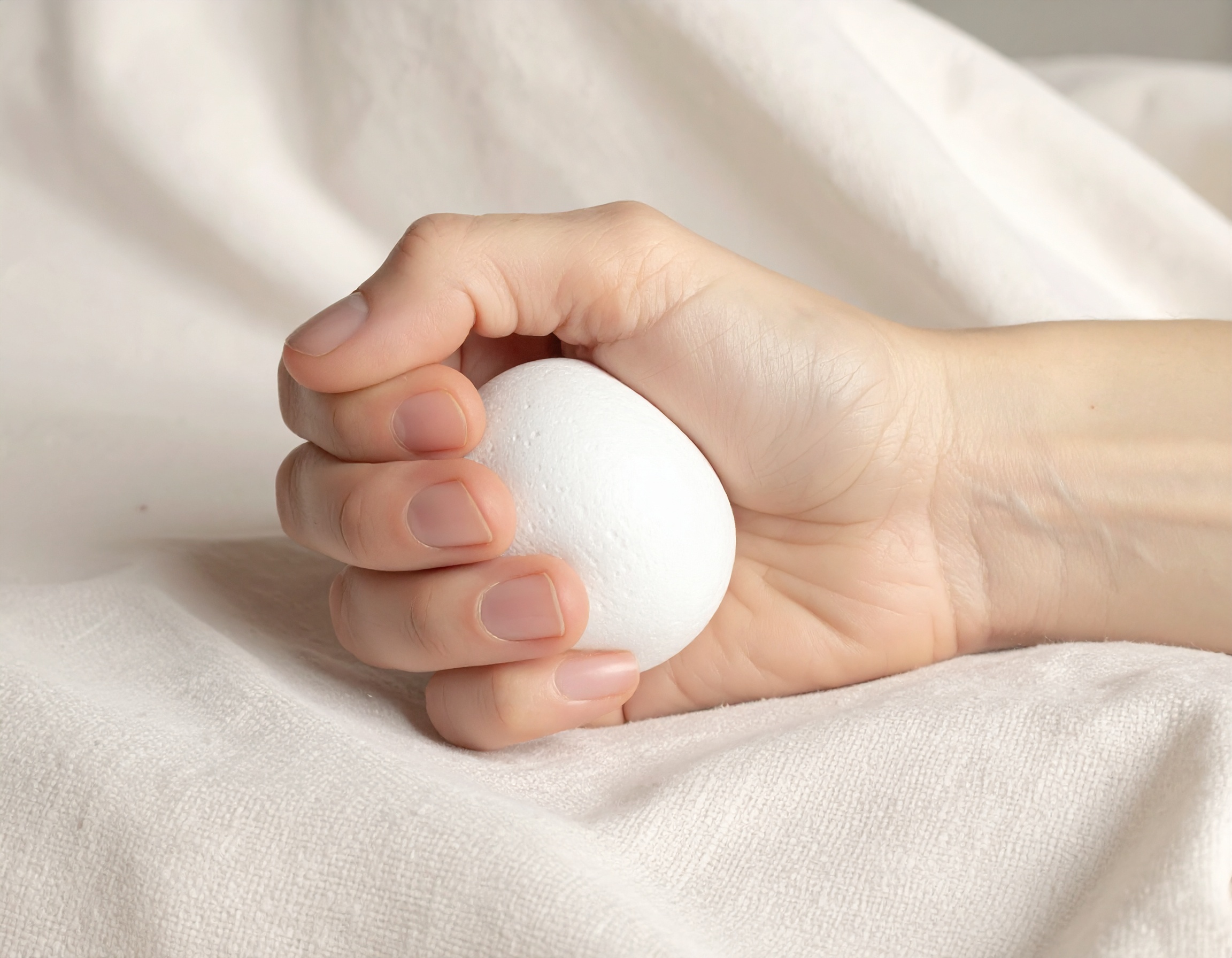 Main tenant une boule blanche sur tissu