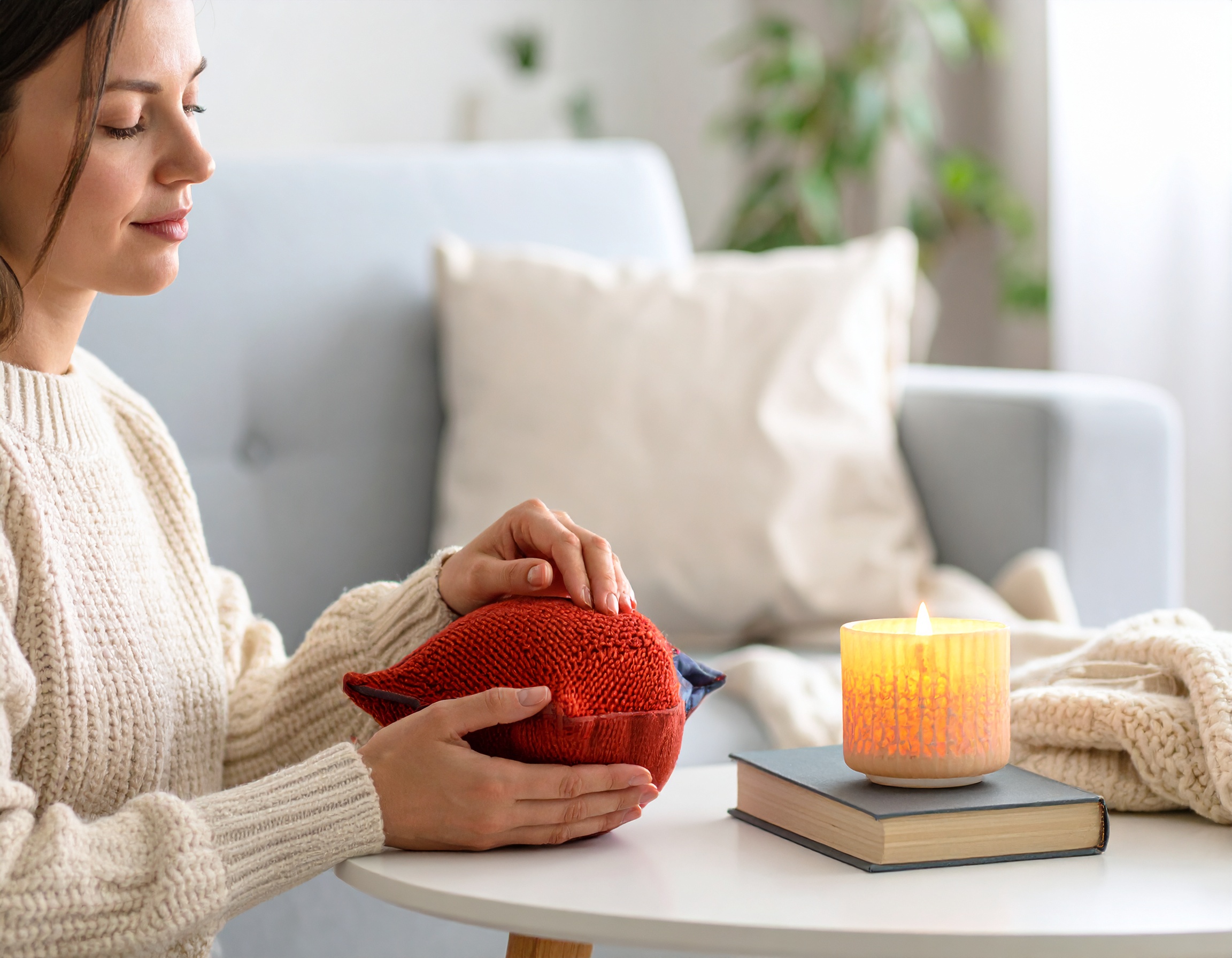 Femme tenant un coussin dans un intérieur cosy.
