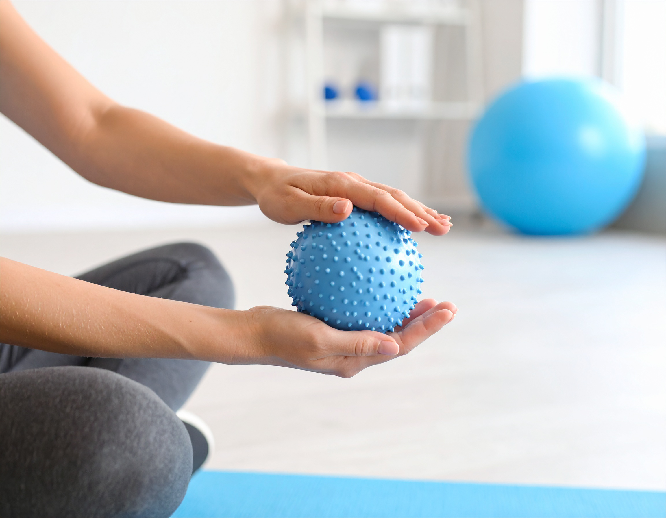 Mains tenant une balle bleue en éponge.
