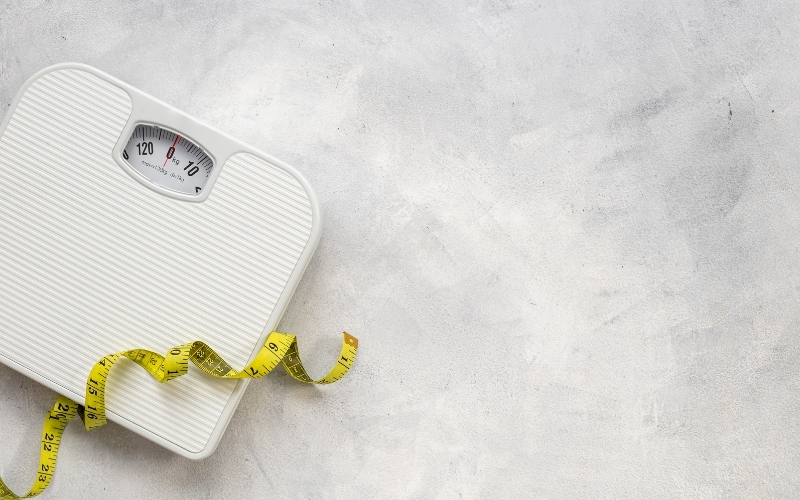 Balance blanche avec un mètre ruban jaune.