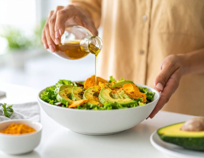 Salade met avocado en olijfolie wordt gegoten.