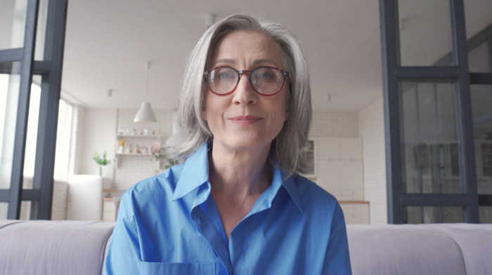 Vrouw in blauwe blouse in moderne woonkamer.