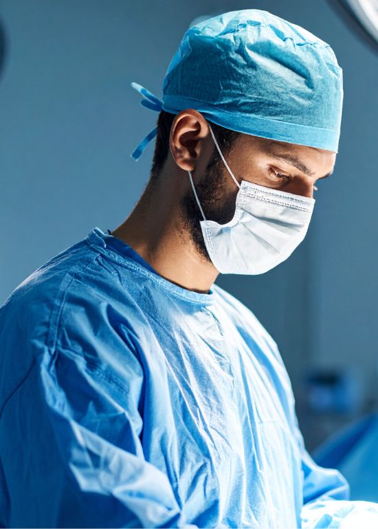 Chirurg in operatiekamer met blauw uniform en masker.