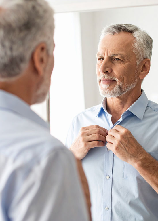 Oude man in spiegel zijn overhemd knoppen dichtmaken