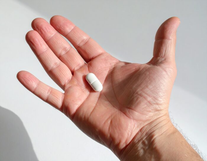 Witte capsule op een handpalm.