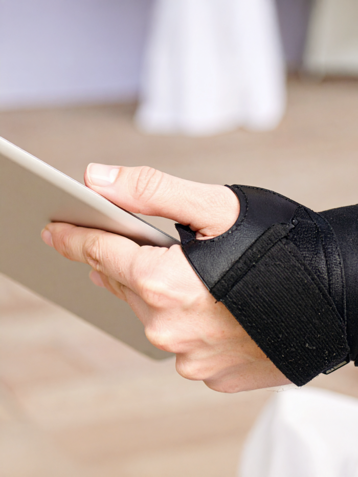 Hand met armsteun houdt een tablet vast.