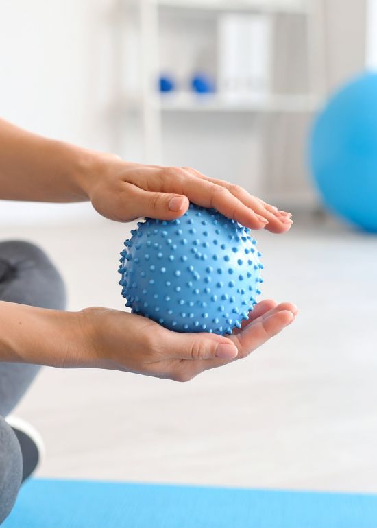 Persoon houdt een blauwe massagebal vast.