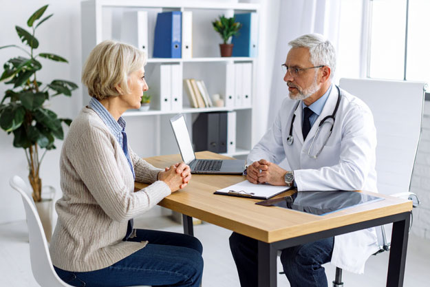 Dokter in gesprek met oudere vrouw in praktijk.